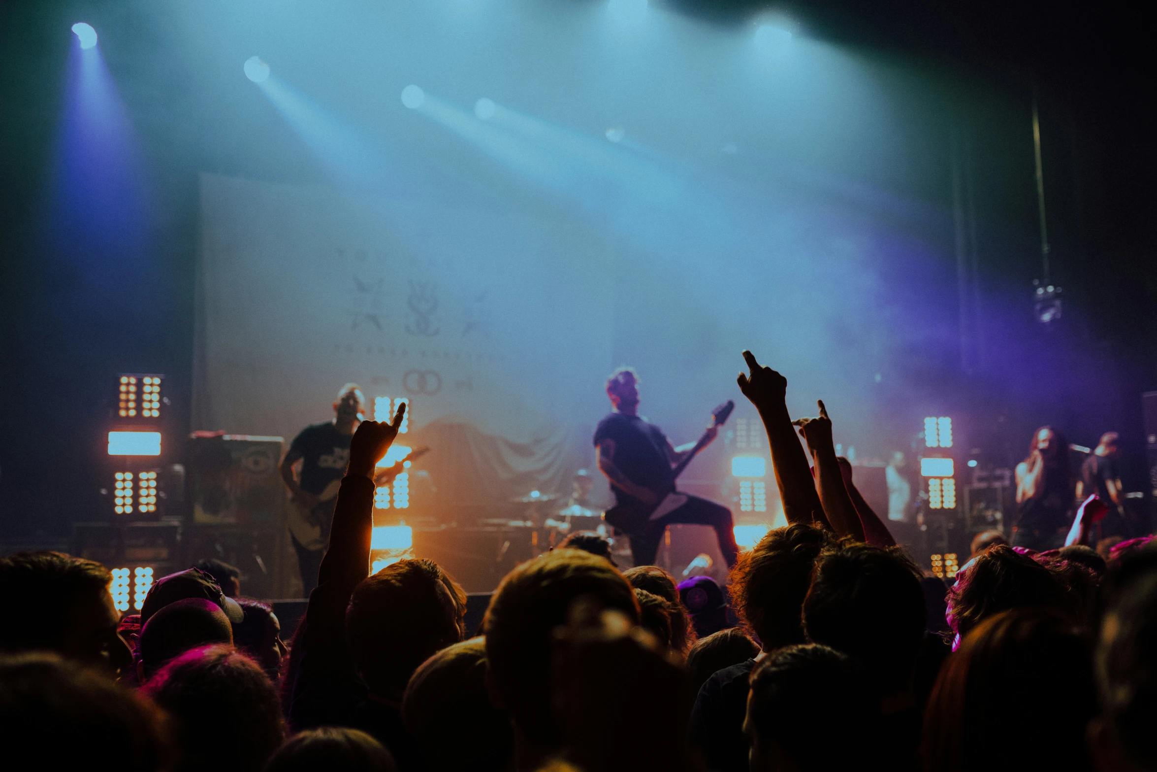 group of people with arms up in the air as an audience looks on