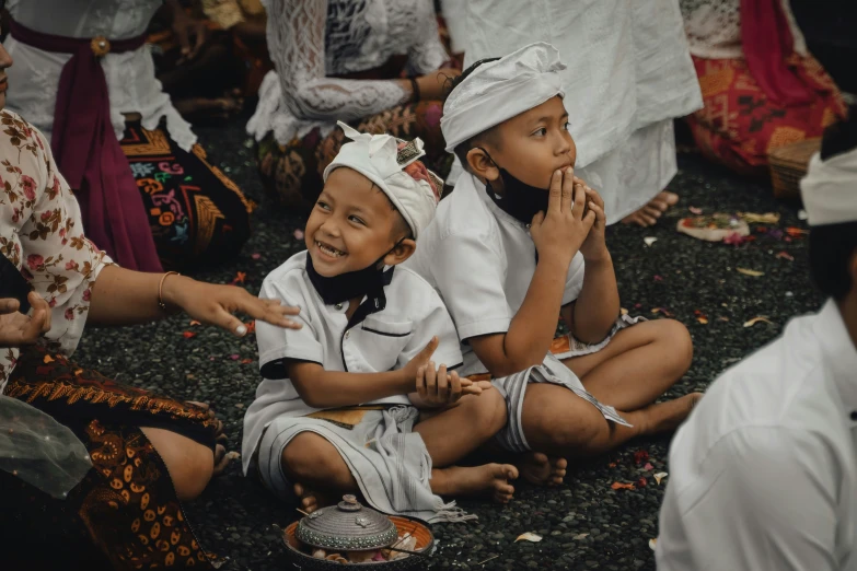 two children sitting and clapping in the grass