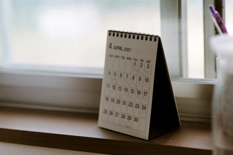 calendar with writing in it sitting on a windowsill by a window