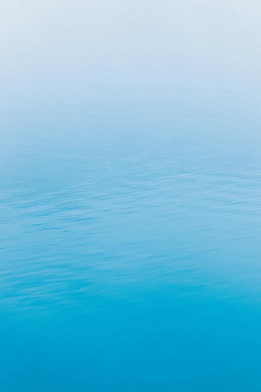 a blue sky with water waves and a boat floating in it