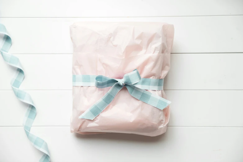 a present wrapped in pink paper with a blue ribbon