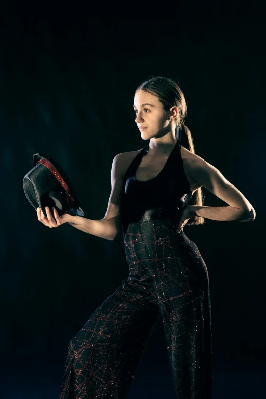 a woman in a black shirt and patterned pants holding a tennis racket