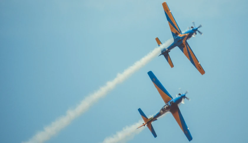 two biplanes flying in the air with smoke coming from them