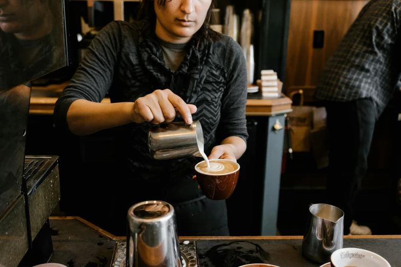 woman holding cup and teaspoon over coffee at counter