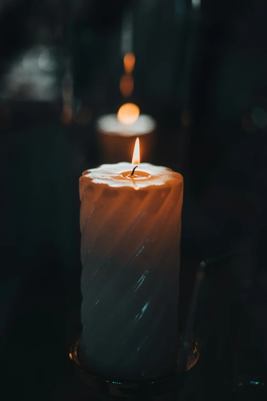 two lit candles sitting on a table in a dark room