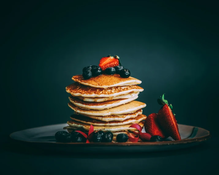 a stack of pancakes with berries and syrup