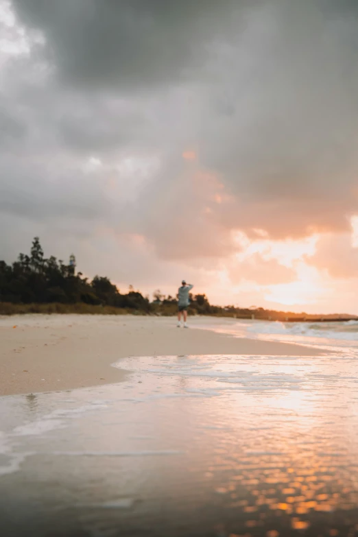 a person walking on the beach near the water with the sky in the background