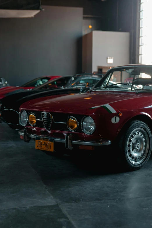 several red classic cars sit parked in a parking garage