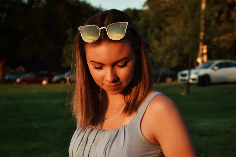 a young lady wearing sunglasses looking down at her phone