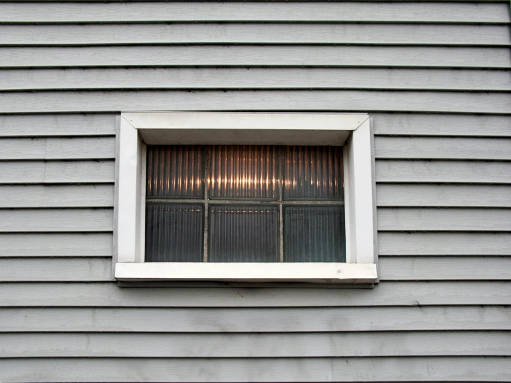 a window on the side of a house that has a curtain drawn