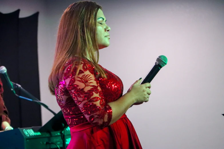 a girl in red and black singing on a microphone