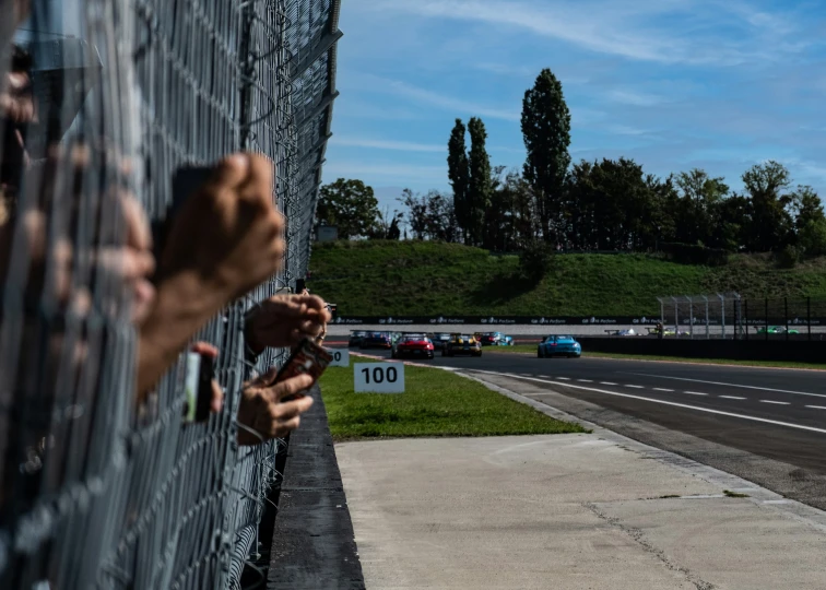 someone is holding their hand to the side of a fence near a road