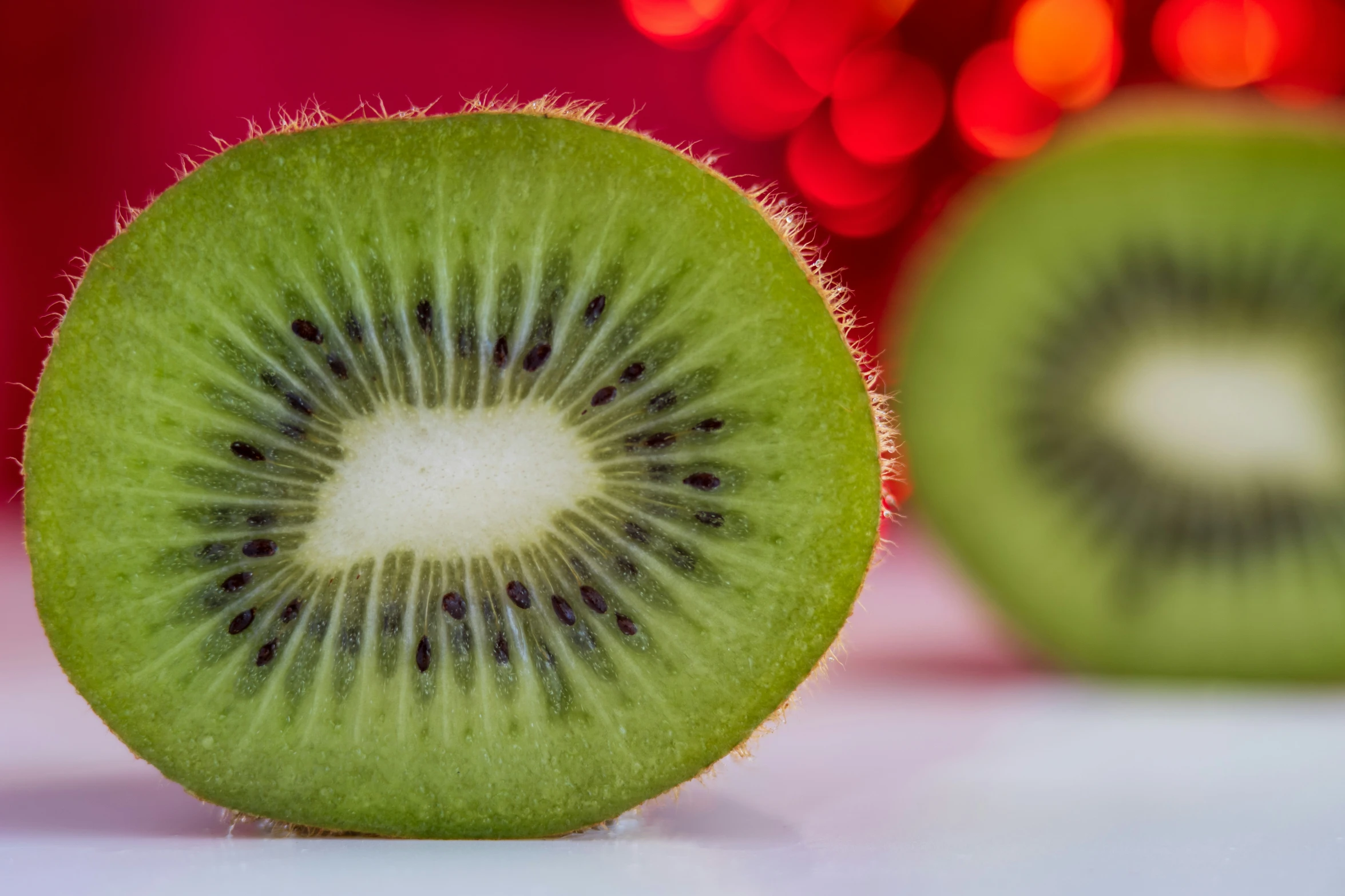 a kiwi fruit cut into half with a red light behind it