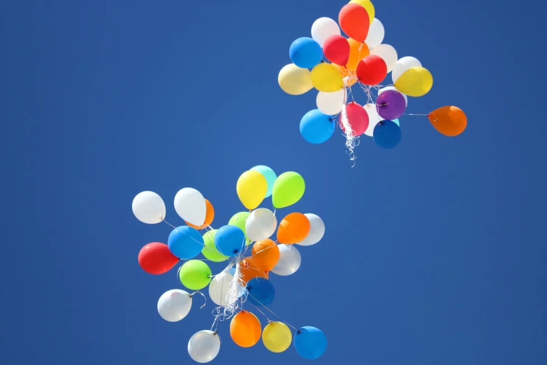 two balloons floating in the air while being flown