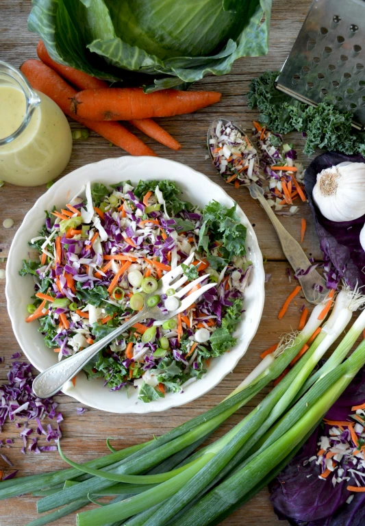 there is a salad in the bowl and vegetables next to it