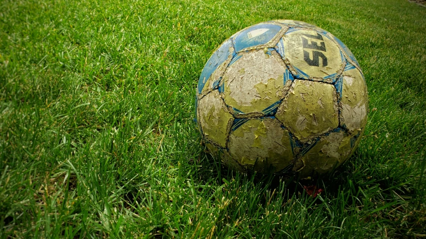 an old worn out soccer ball sitting on the grass