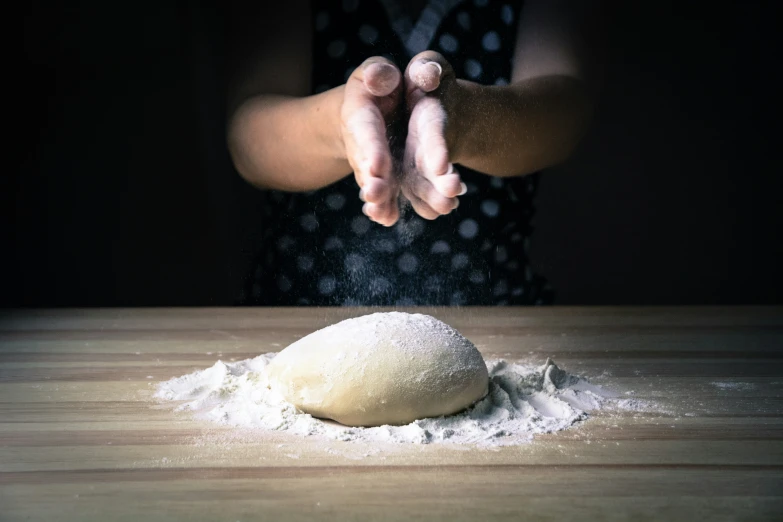 there is an uncooked ball of dough and the person has their arms in the air