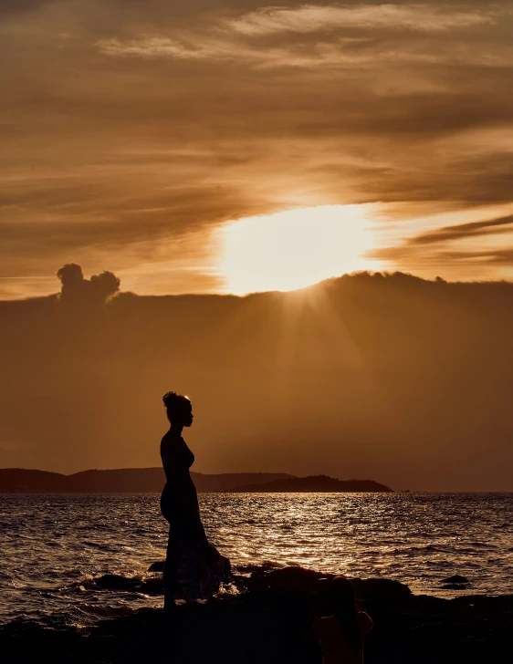 woman walking in the sun at sunset over the ocean