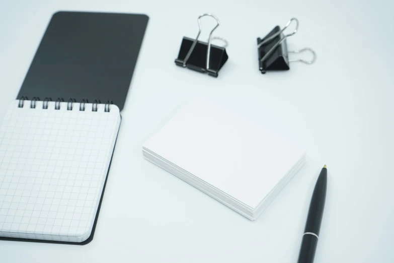 a notebook, pen, and clipboard resting next to a pair of scissors