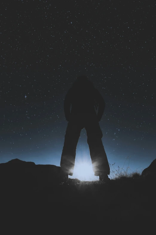 person in silhouette standing on top of a hill with the sun shining down