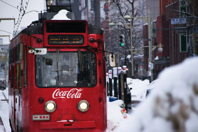 the red train is riding down the snowy street