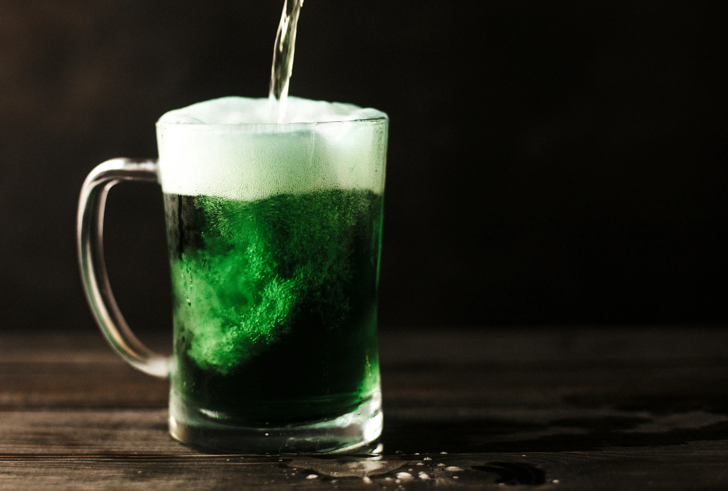 green liquid being poured in a glass of drink