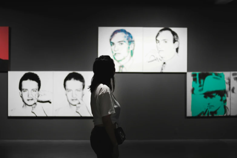 a person walking in front of four wall paintings