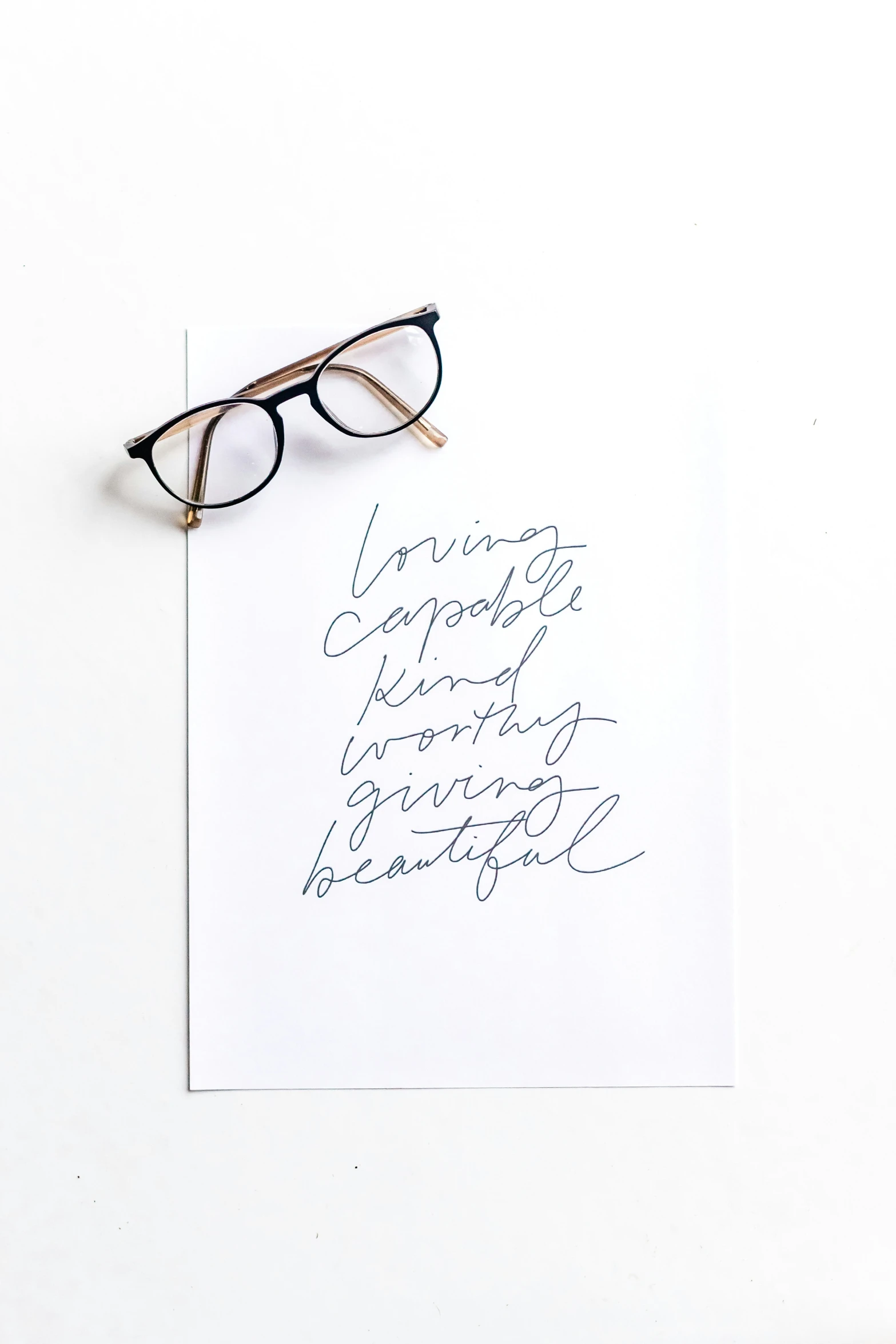 a piece of paper has writing on it and a pair of eyeglasses resting on it