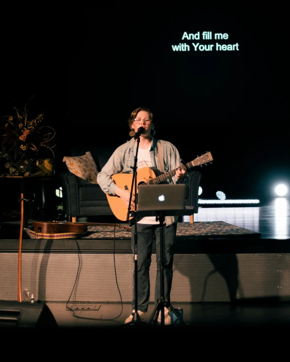 man singing and playing music on a stage with a quote above him