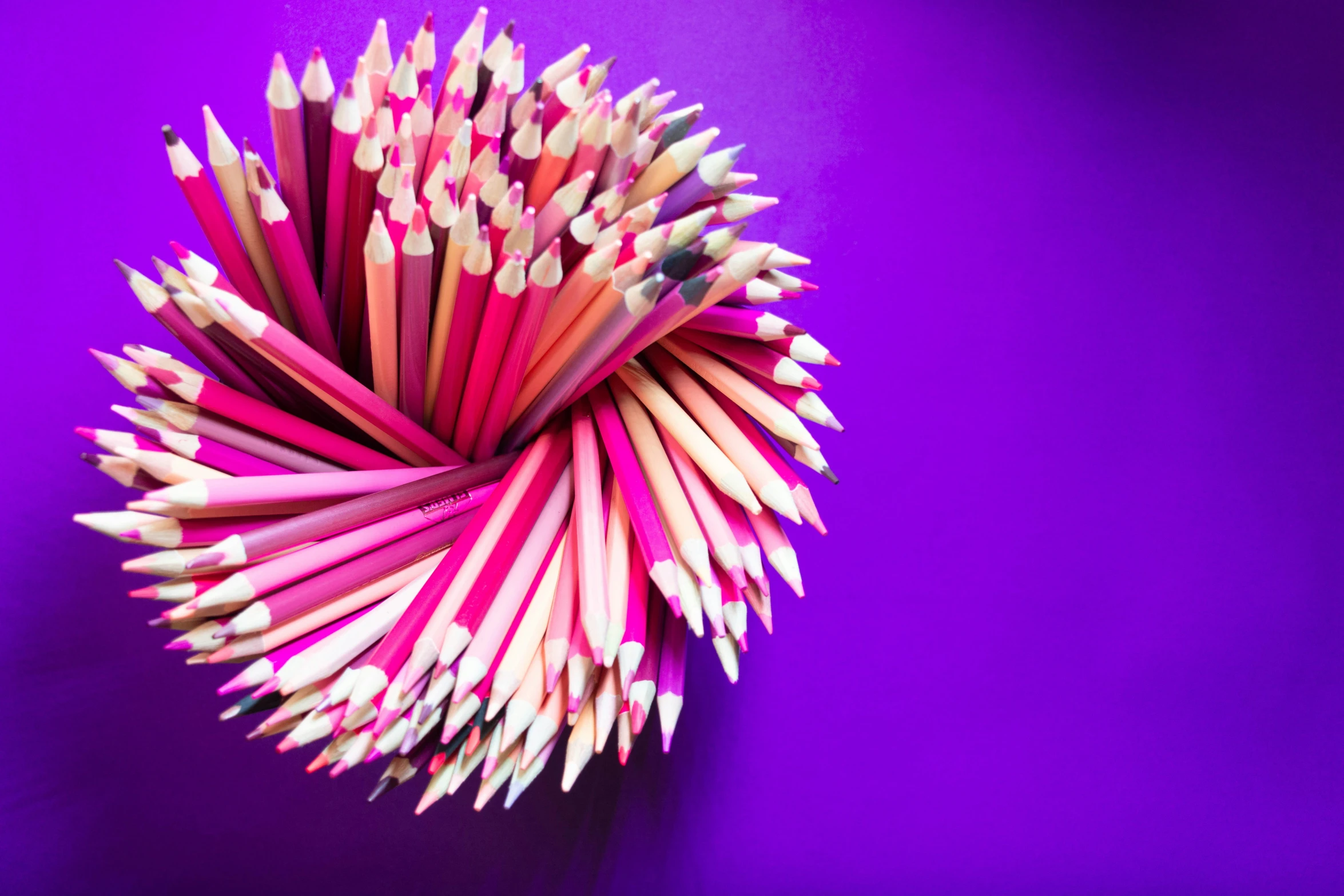 the colored pencils are all arranged in a spiral on purple