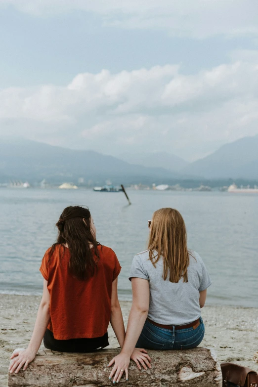 two women sitting next to each other on a beach