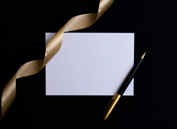 an empty notecard, golden ribbon and a pen