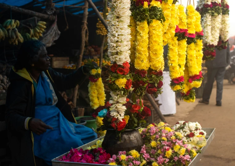 a woman arranging the flowers in a market place