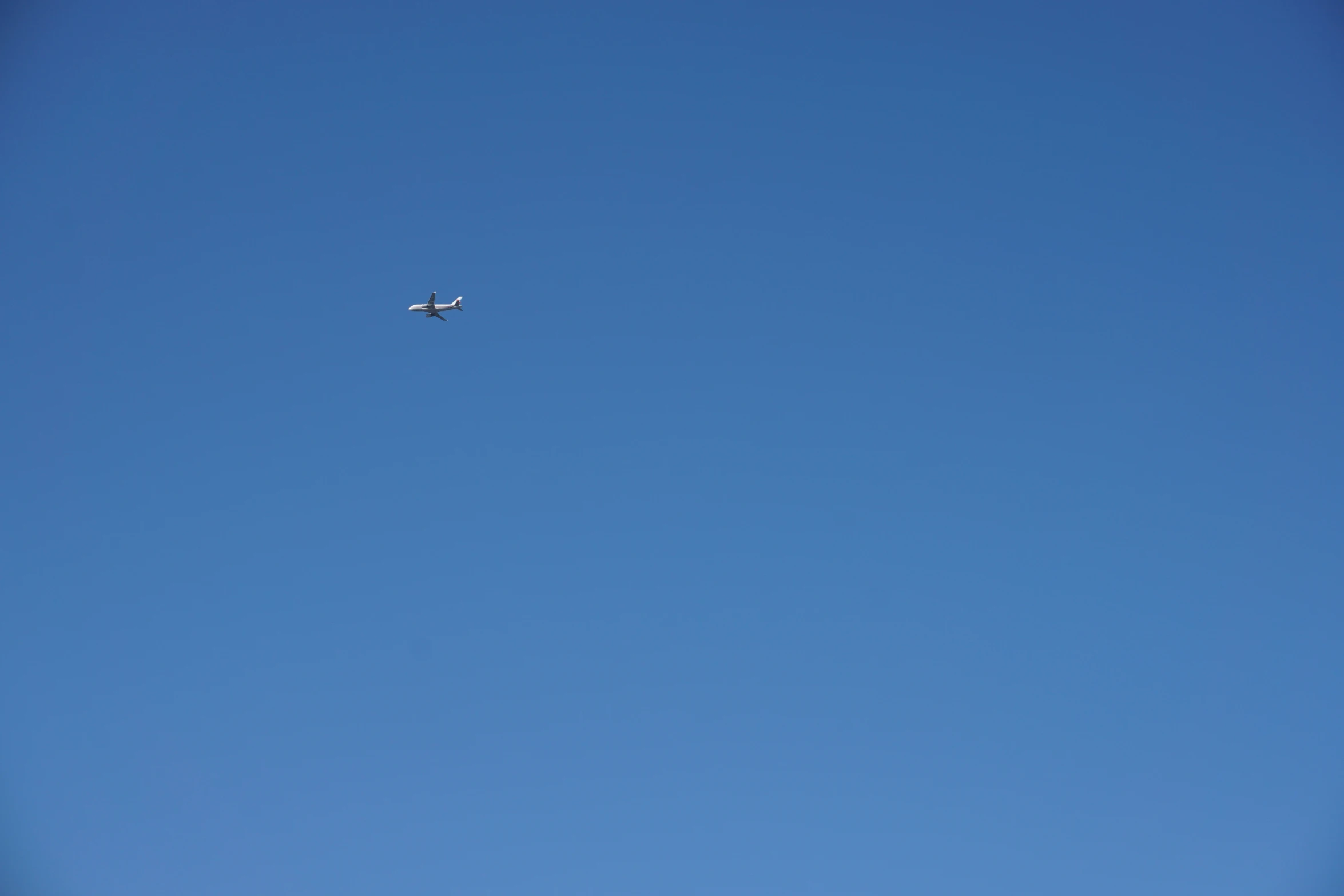 a plane flying in a blue sky under a cloudless day