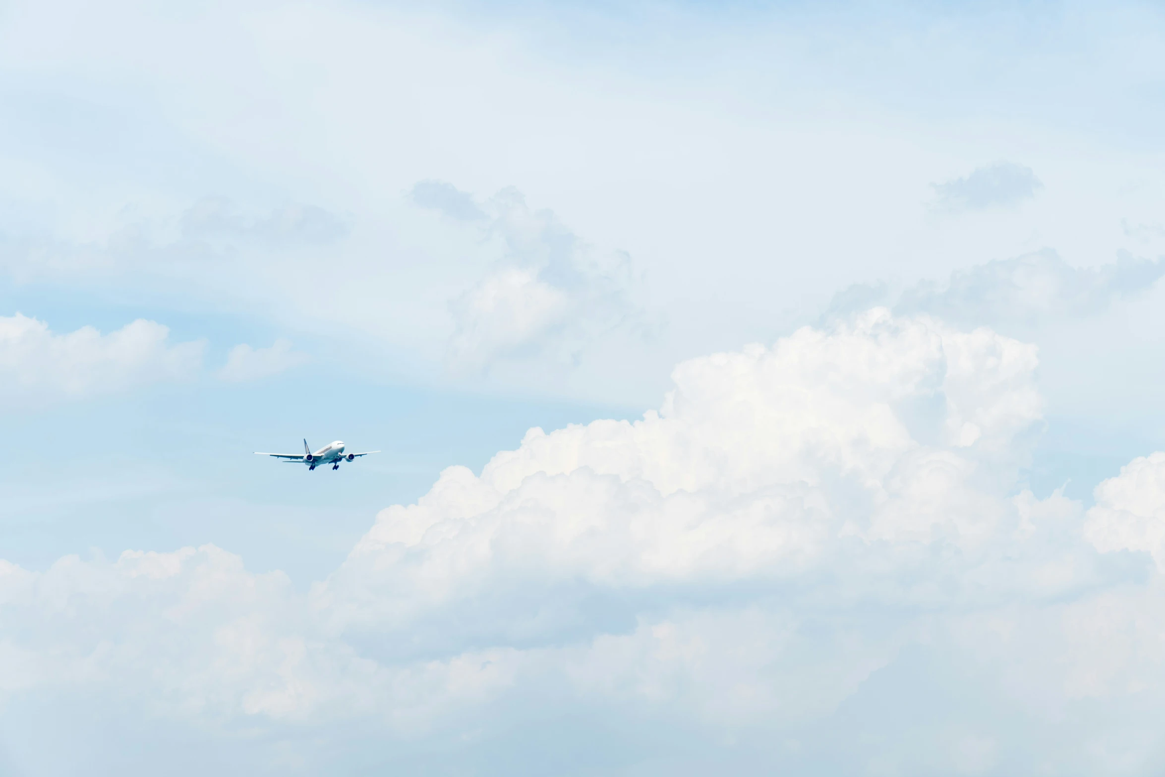 an airplane flying through the blue cloudy sky