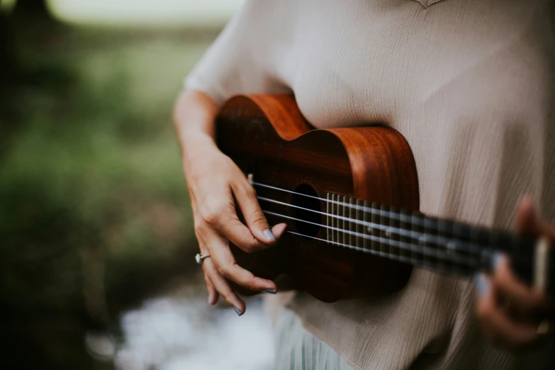 close up of woman playing ukulele outdoors, slow motion