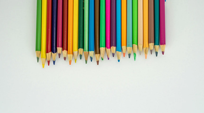 a row of colored pencils laying in front of a white background