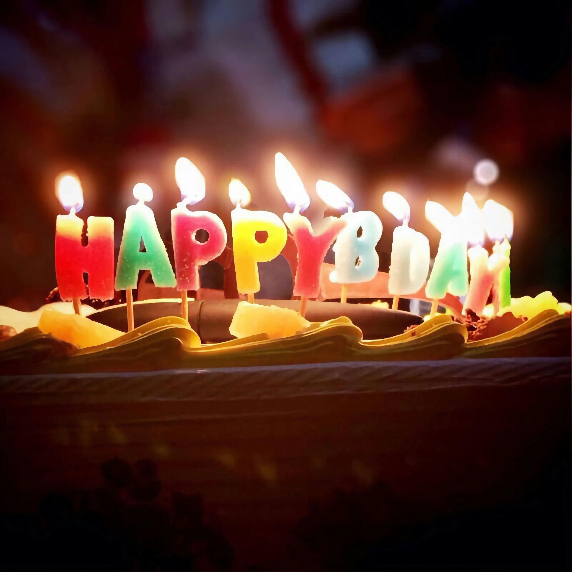 a cake that has candles in it with the word happy written on it