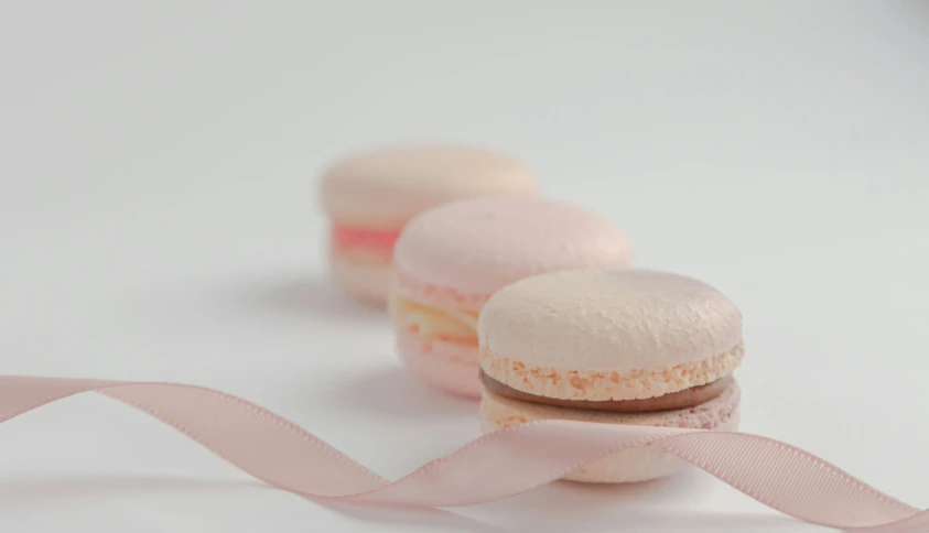 two pink macaroons on a light colored table