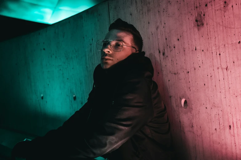 a man leaning against a wall in the dark