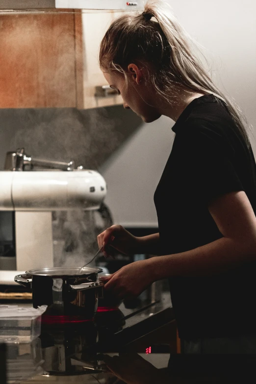 woman in black shirt preparing food in stove top oven