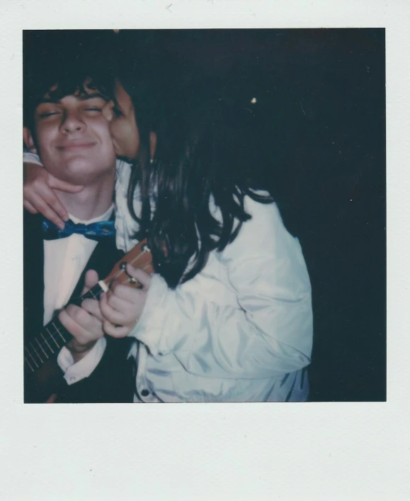 a man and a woman in tuxedo singing into an electric guitar