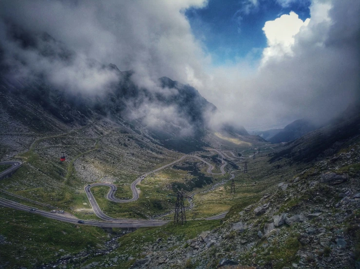 a cloudy sky above a winding road with cars driving on it