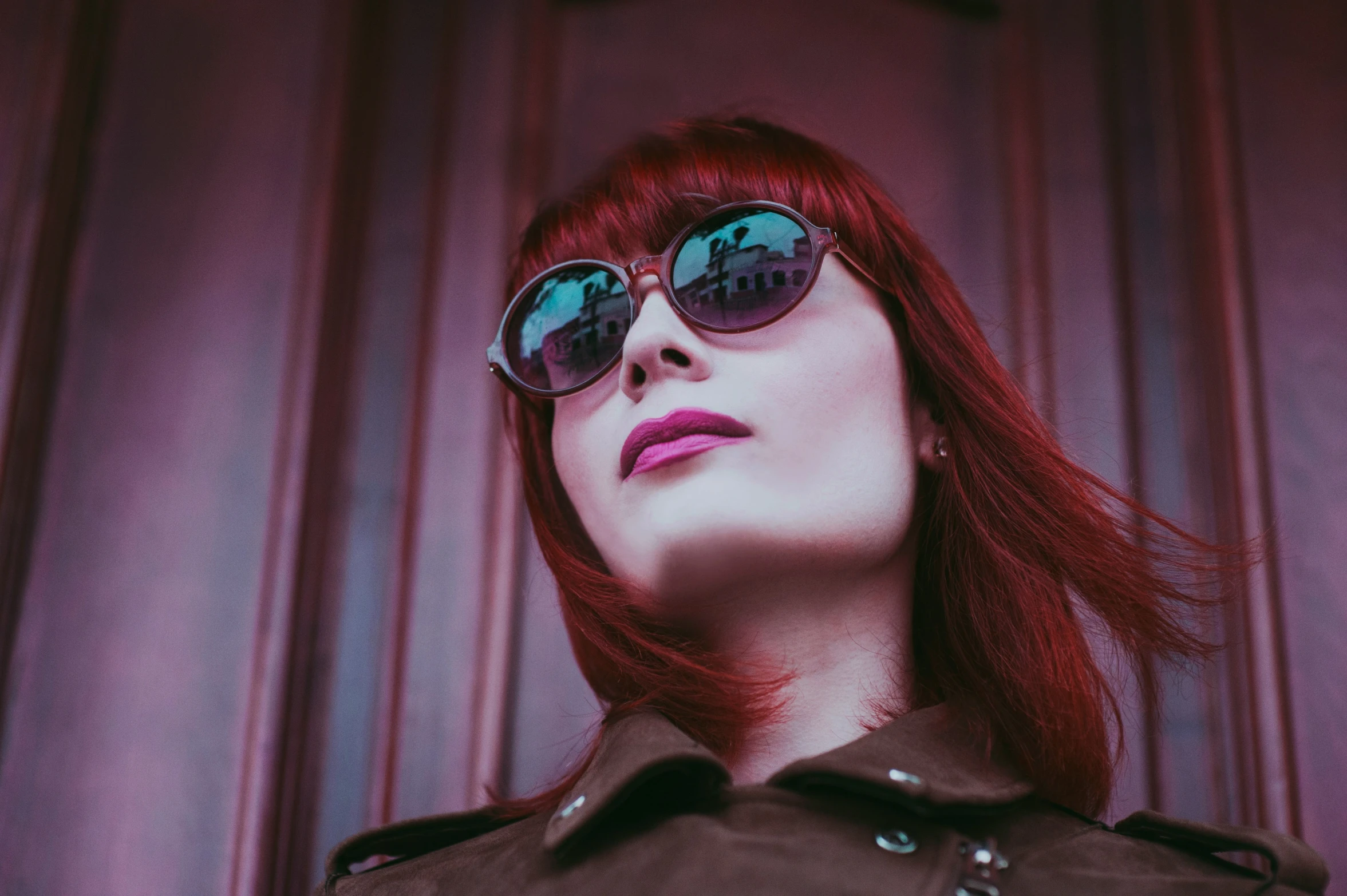 a woman wearing shades is leaning against a wall