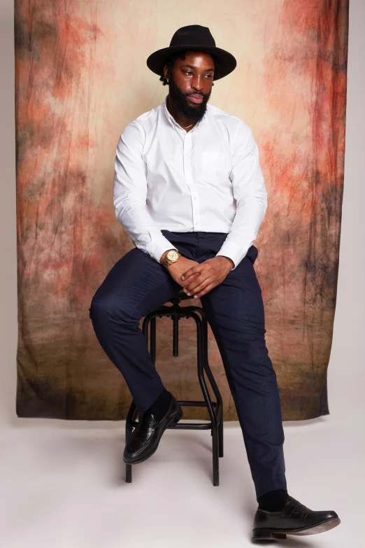 a man sits on a chair with his hands in his pockets