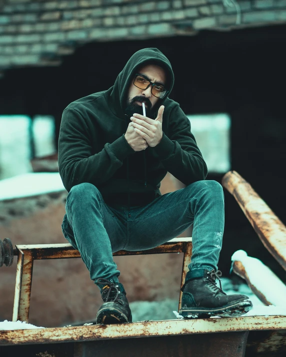 a man sitting on top of a rusty object with his fingers in his mouth