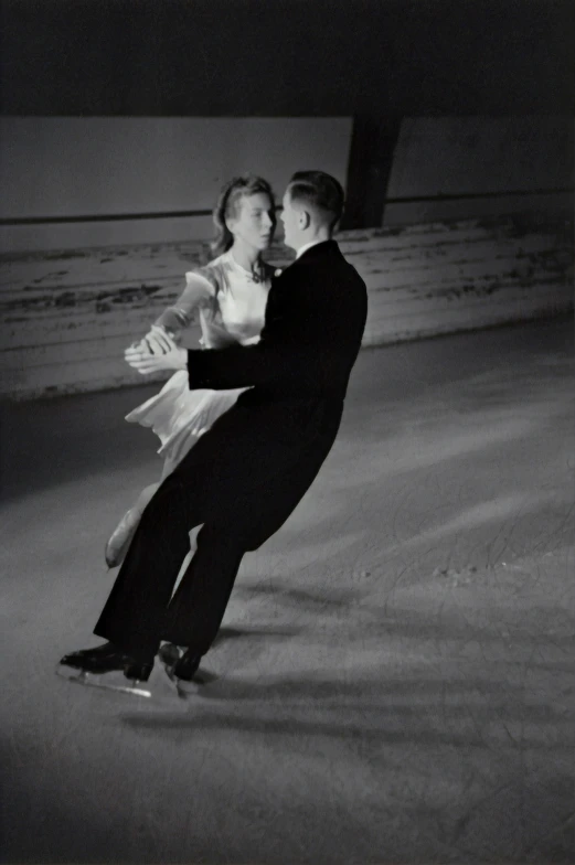 two people are skating on ice together at night