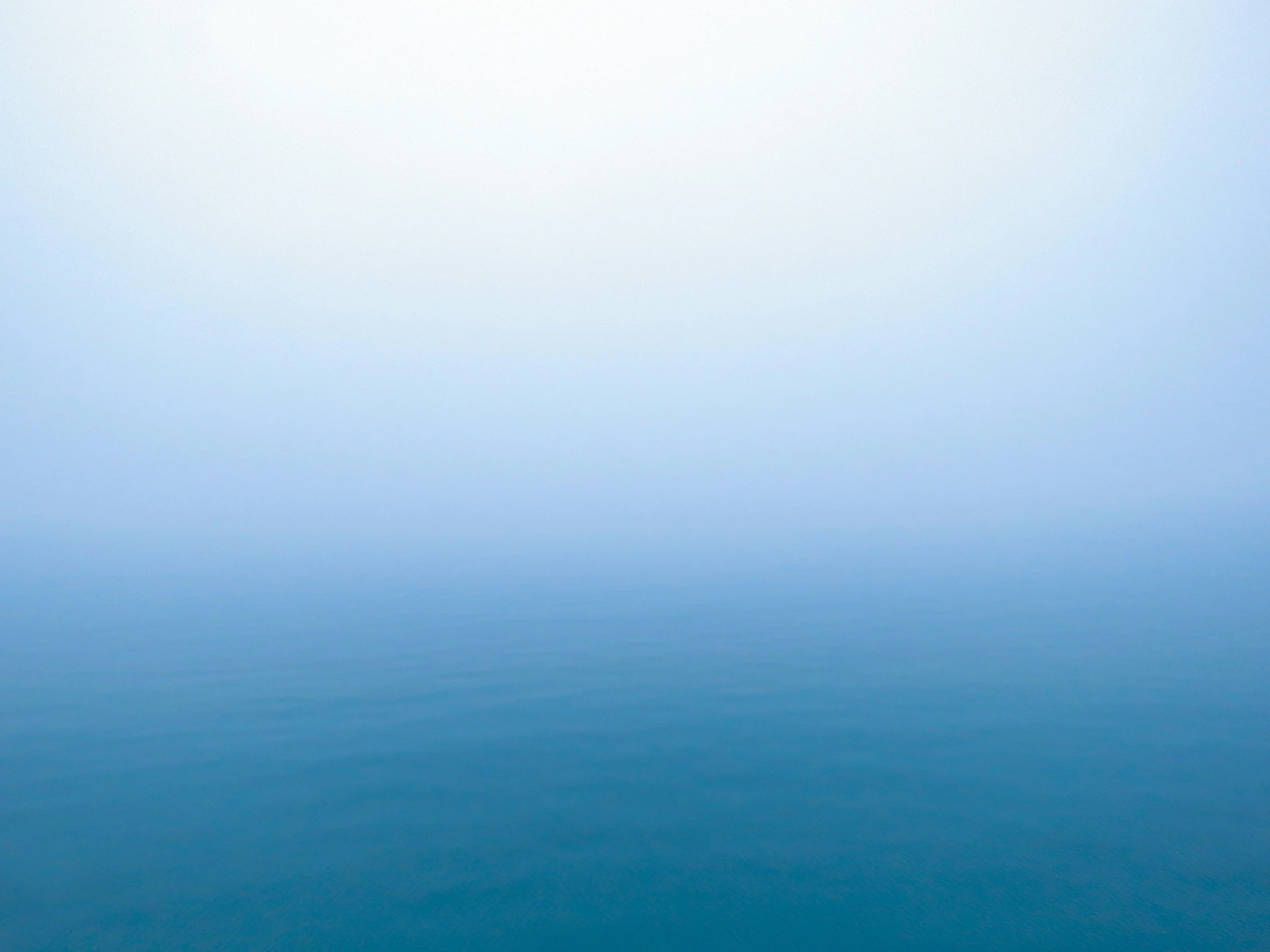 a foggy ocean with a lone boat on the water