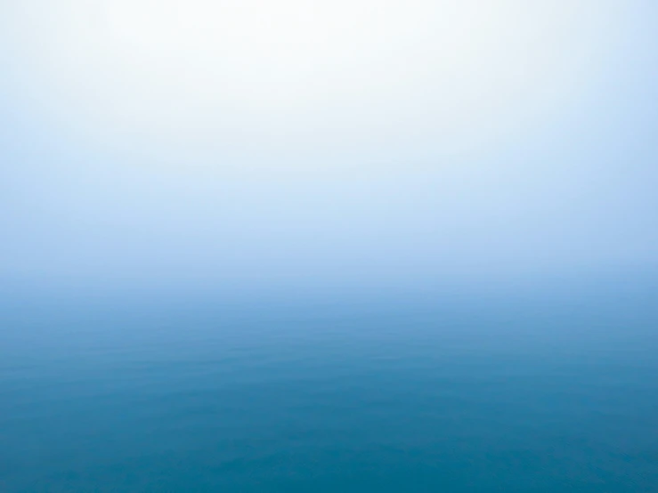 a foggy ocean with a lone boat on the water