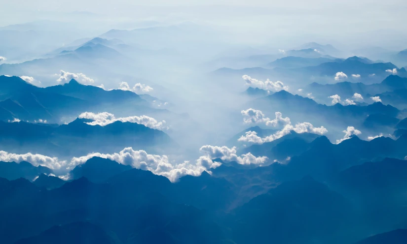 a view from an airplane of some clouds and mountains